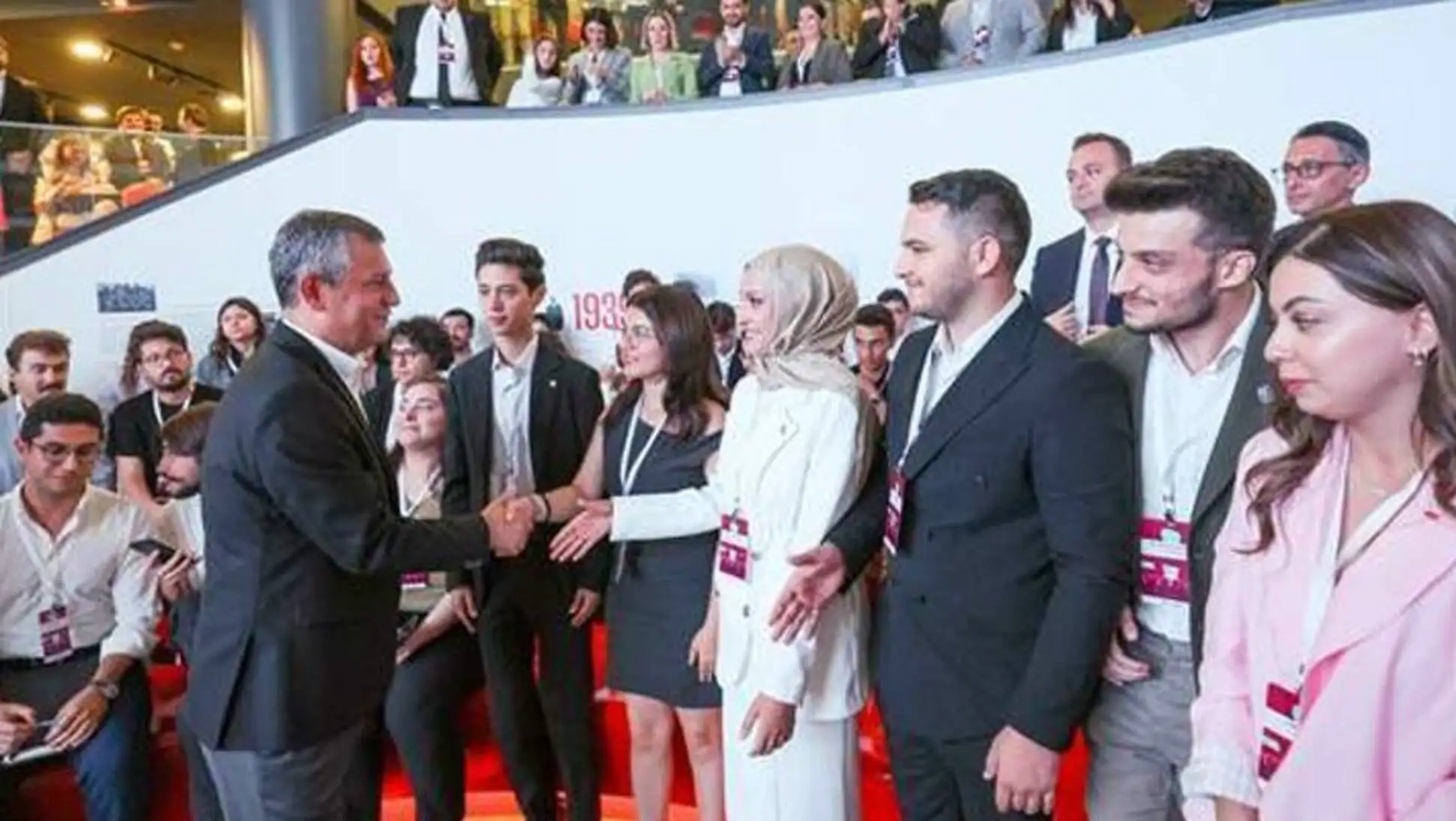 Özgür Özel, gençlerle el sıkışıyor.