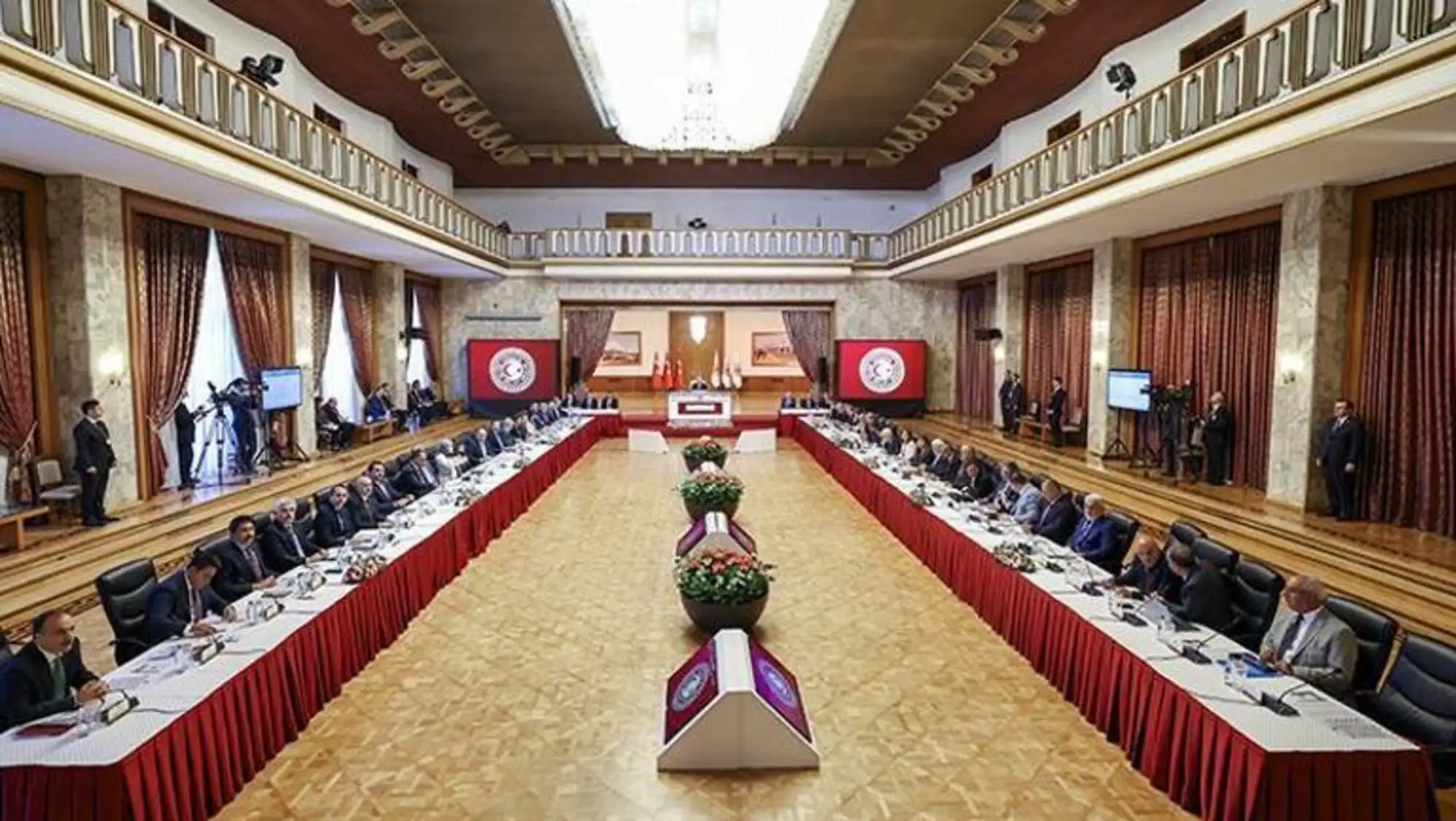 Büyük bir odada masalarda oturan bir grup insan.