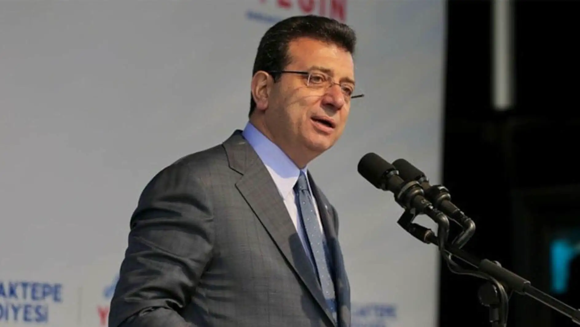 Ekrem İmamoğlu, mikrofonla konuşan bir adam. Ekrem İmamoğlu, mikrofonla konuşan bir adam.