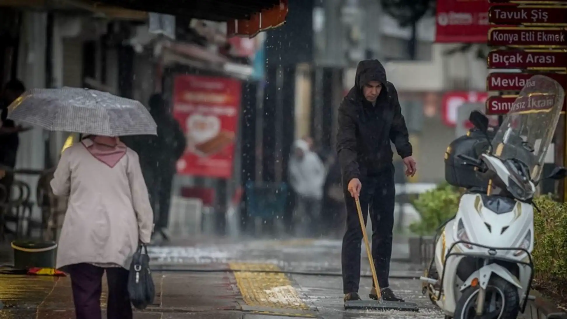 A man sweeping the sidewalk in the rain. A man sweeping the sidewalk in the rain.