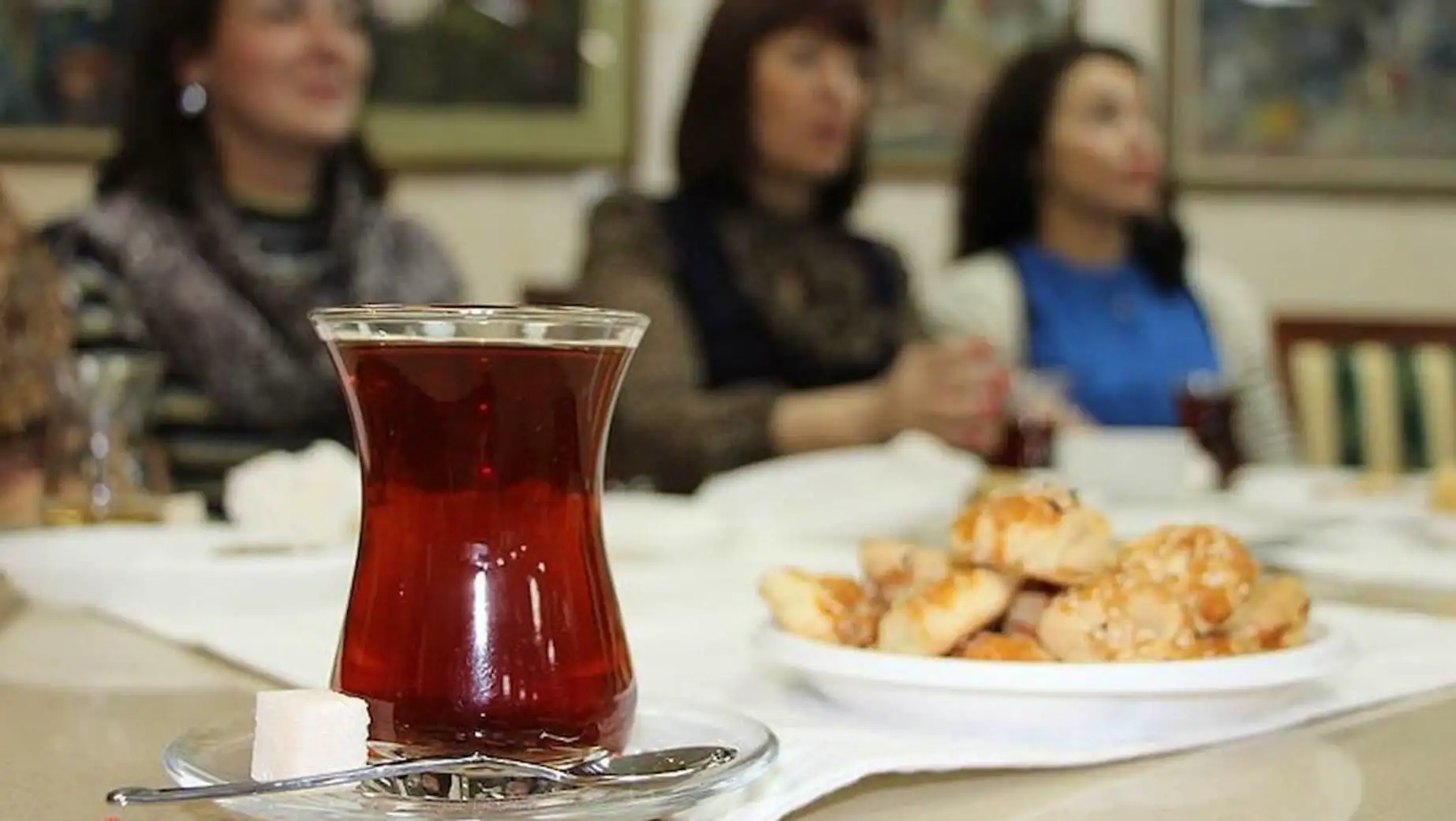A glass of tea on a table with a plate of food.