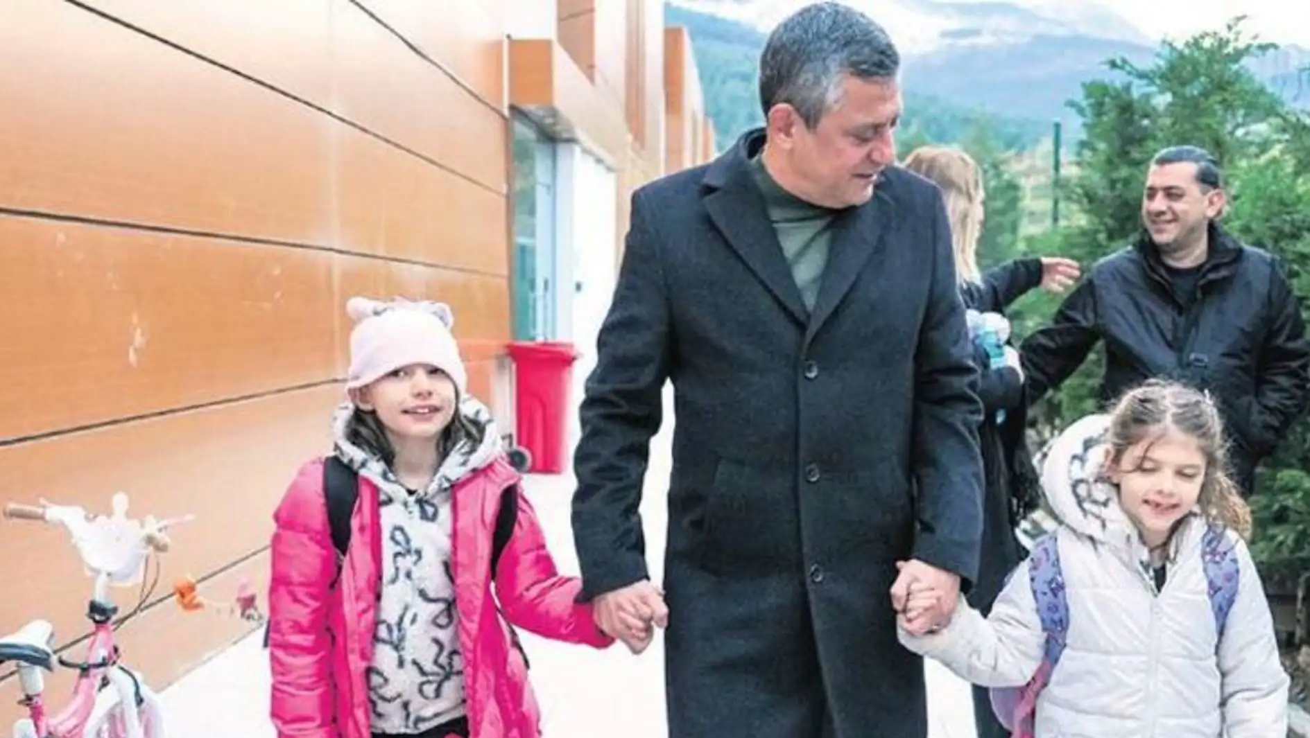 A man holding hands with two children.